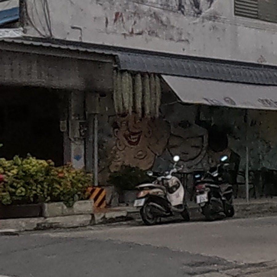 Faded painted smiling character face on ground-floor wall