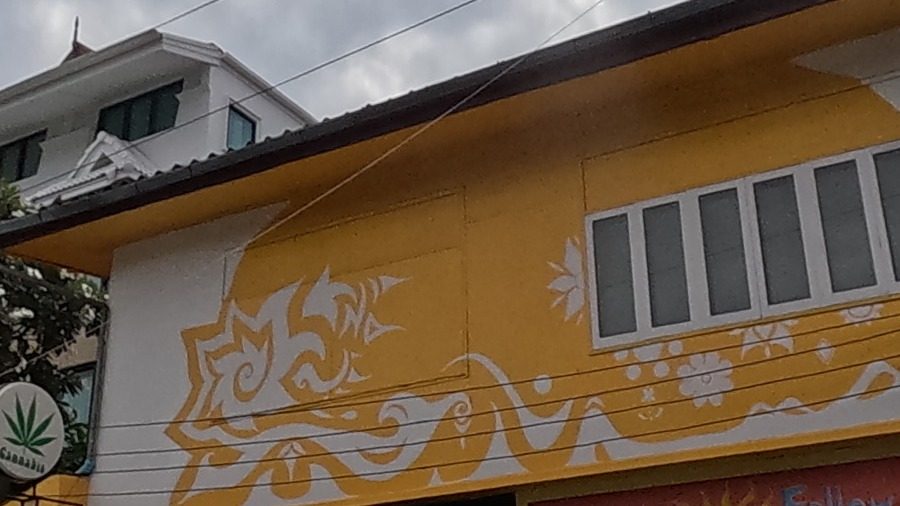 Yellow building facade painted with white tribal-floral swirl mural