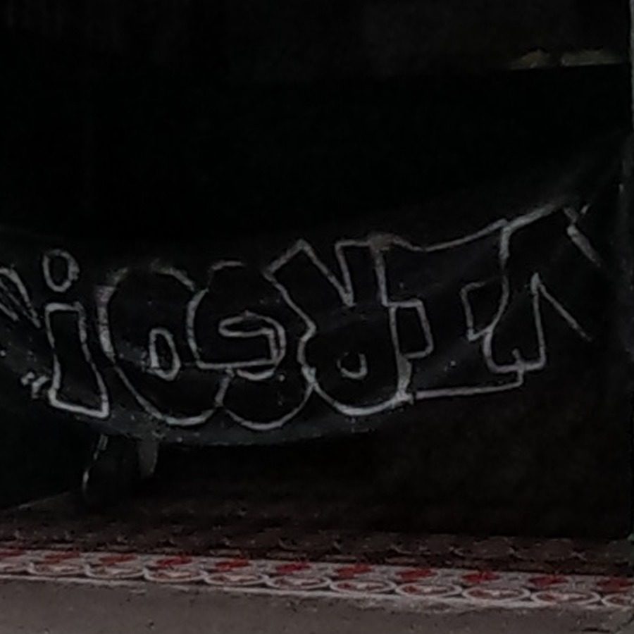 White-outline bubble tag on dark shopfront shutter