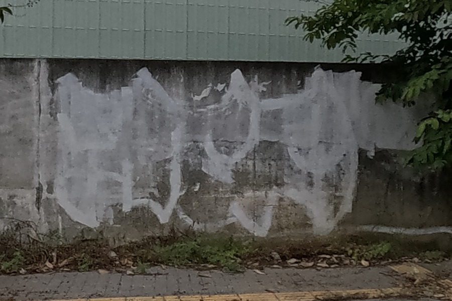 White tag on a low wall under trees