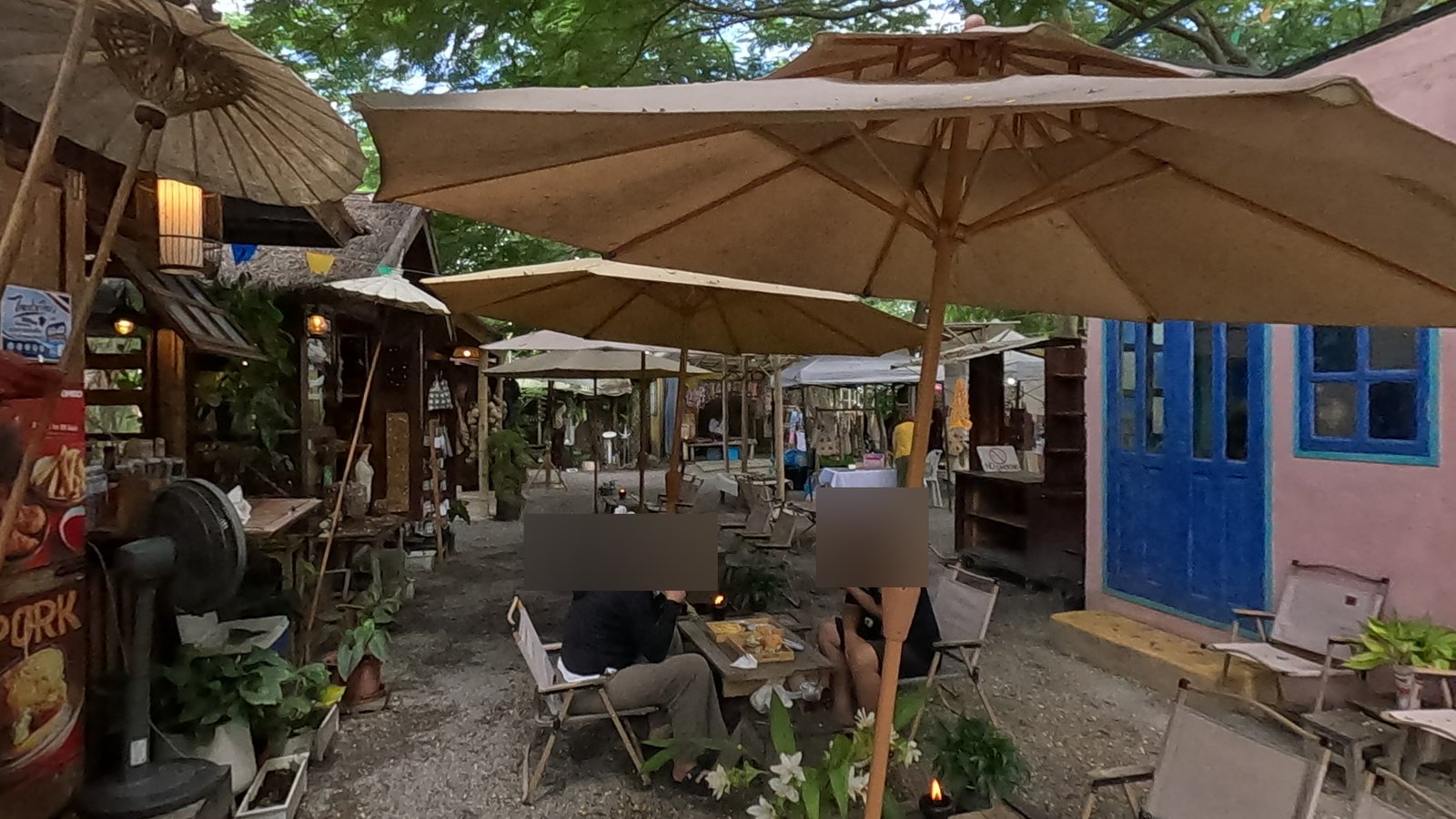 Café tables under umbrellas by the pink house — Chamcha Market, San Kamphaeng