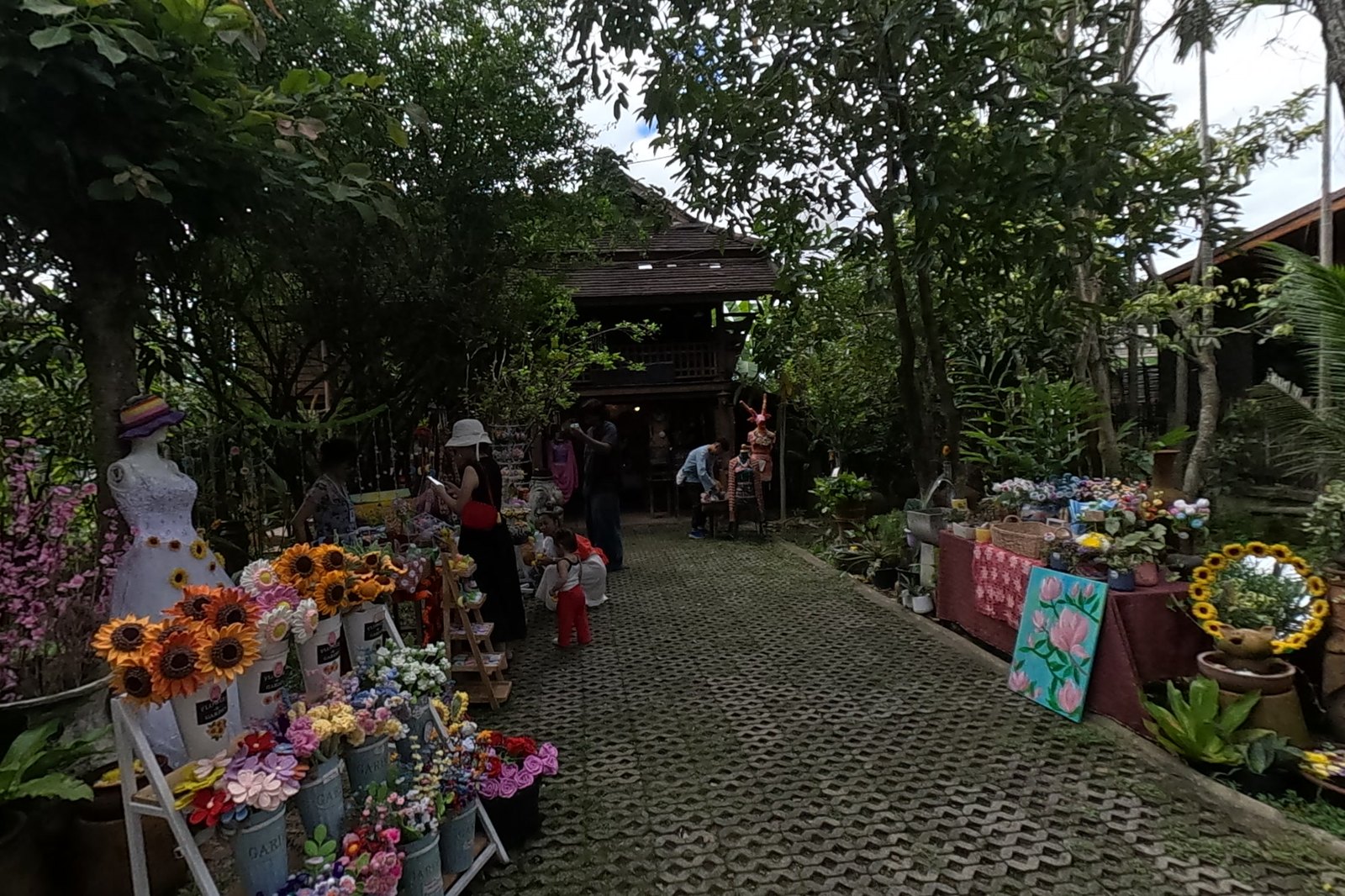 A garden path of crochet flowers to a teak house — Chamcha Market, San Kamphaeng