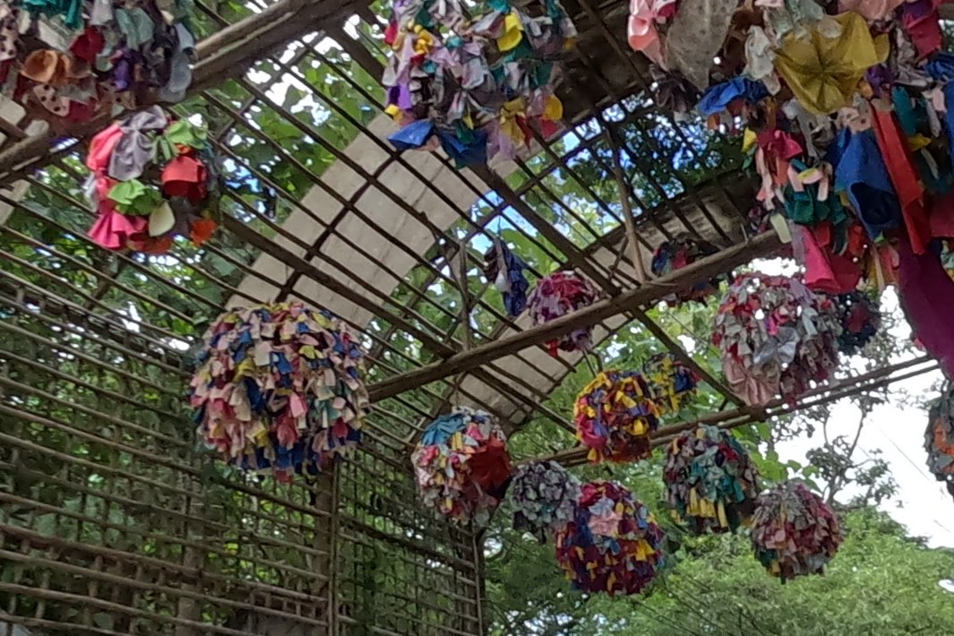 Rag pom-poms over the bamboo arch — Chamcha Market, San Kamphaeng
