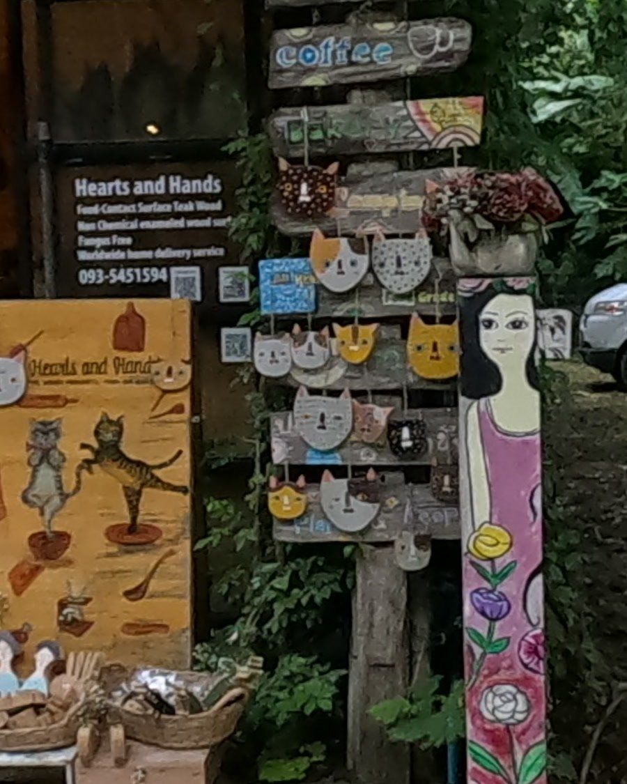 Painted wooden cat faces at Hearts and Hands — Chamcha Market, San Kamphaeng