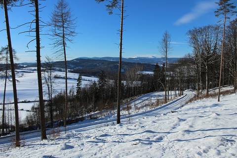 Hairpin turn between Chvaleč and Adršpach on route number 30110. Zlatá Olešnice wind farm and East Giant mountains ridge panorama at the background.