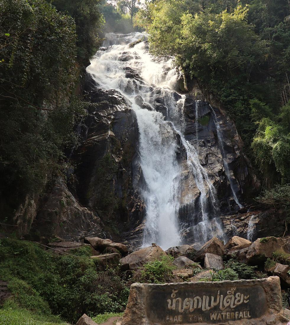 Mae Tia Waterfall, a magnificent cascading waterfall set within the verdant forest of Op Luang National Park, Chiang Mai, Thailand. The image captures the natural beauty of the waterfall as it flows d