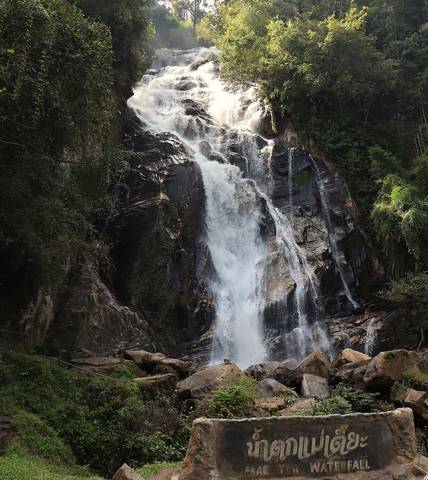 Mae Tia Waterfall, a magnificent cascading waterfall set within the verdant forest of Op Luang National Park, Chiang Mai, Thailand. The image captures the natural beauty of the waterfall as it flows d