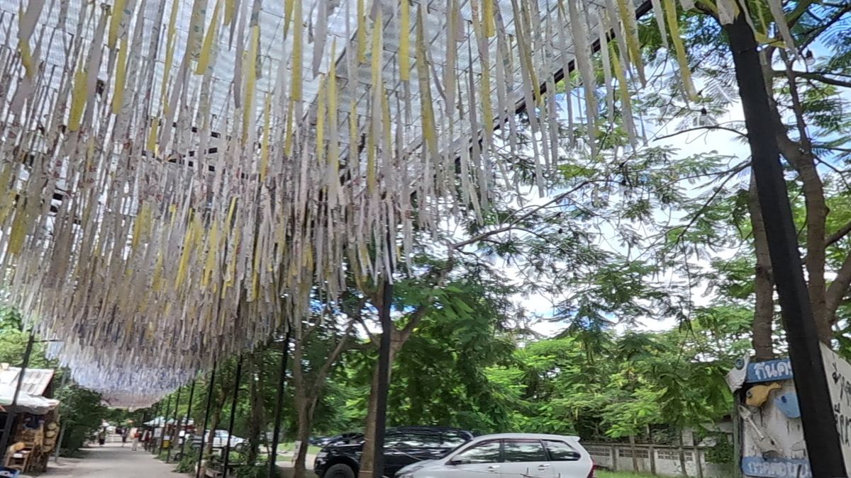 ริ้วกระดาษห้อยเต็มเพดานทางเดิน · A ceiling of paper streamers over the lane