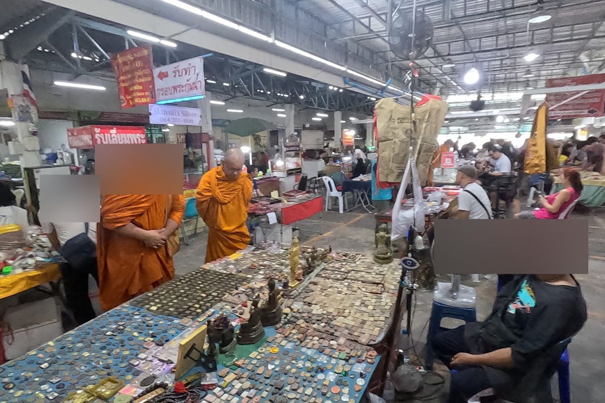 พระภิกษุเลือกดูพระเครื่องบนโต๊ะยาว · Monks browse a long amulet table