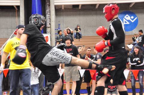 Fighter throwing a lowkick during an amateur muay thai competition.
