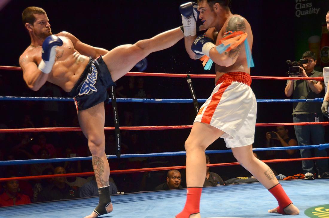 Muay Thai competitor attempts a high kick but it is blocked by his opponent.