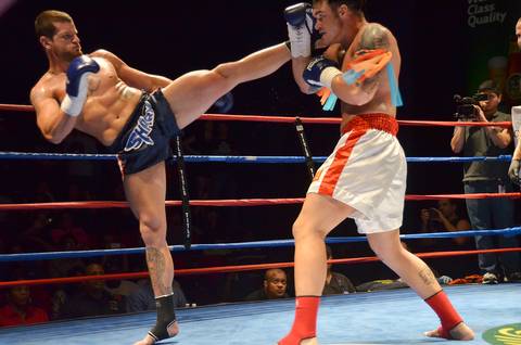 Muay Thai competitor attempts a high kick but it is blocked by his opponent.