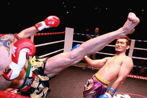 A fighter leans back to evade a round kick