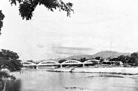 This picture is described as follows:
Original caption: "A bridge over the Wang River, Lampang."
Uploader's caption: Perhaps referring to Ratsadaphisek Bridge.