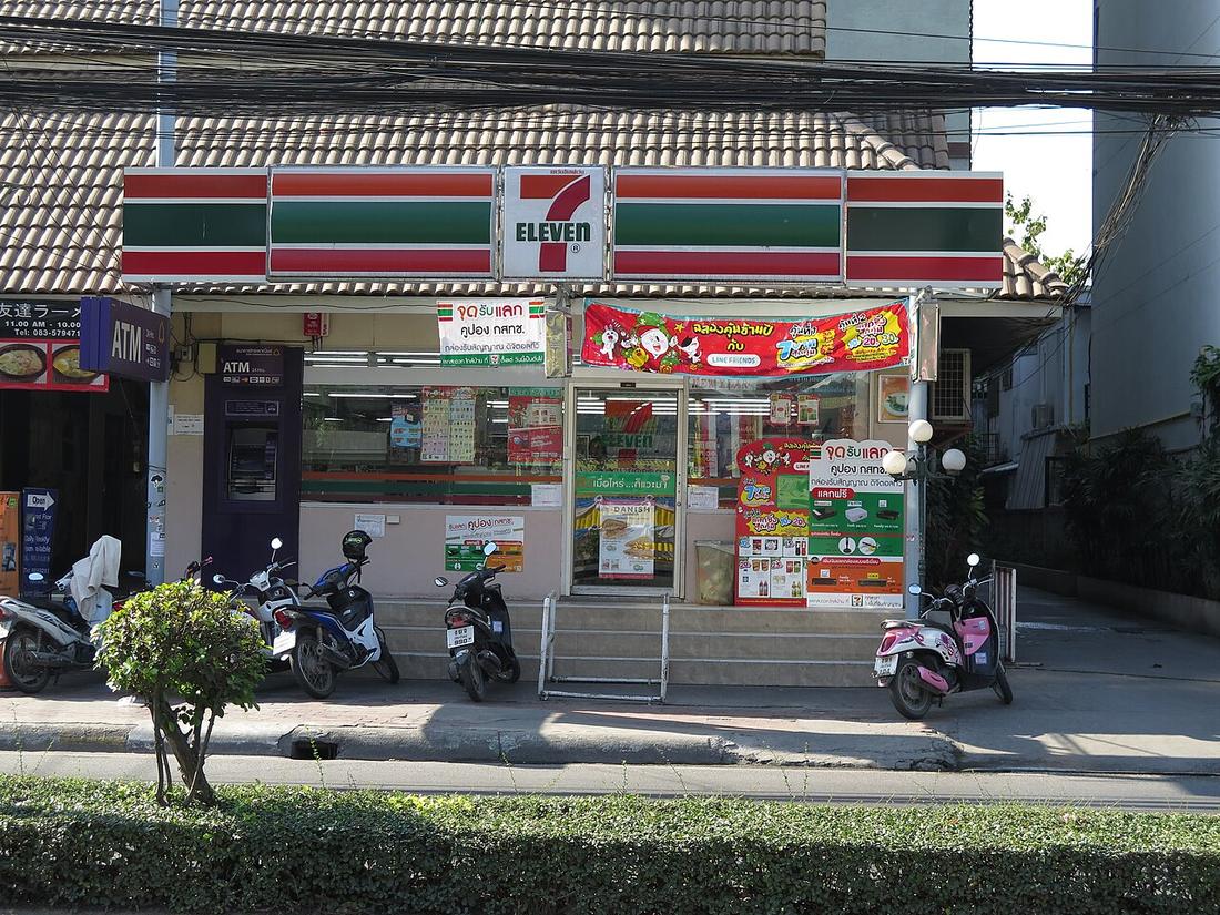 A Seven-Eleven store front complete with motorcycles.  Chiang Mai, Thailand.