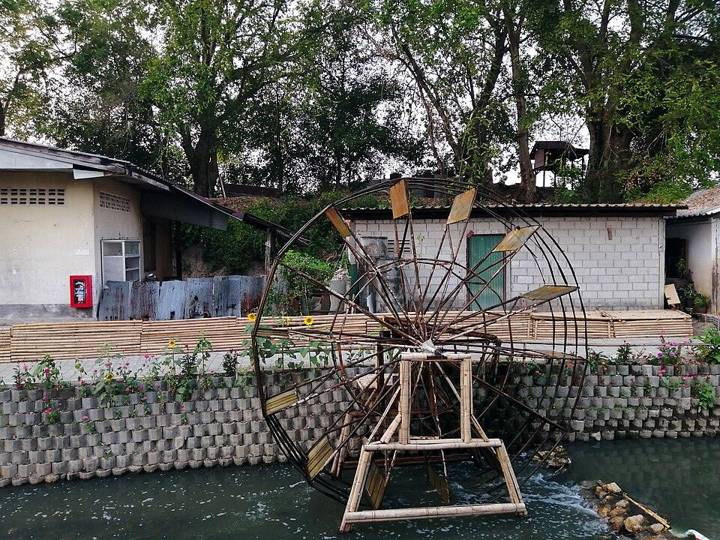 Een waterrad dat door het water wordt bewogen, met op de achtergrond ook nog de oude stadswallen zichtbaar.