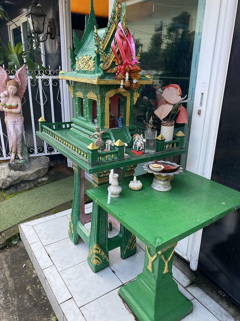 ศาลพระภูมิสีเขียว หน้าร้าน · a bright green spirit house outside a shopfront