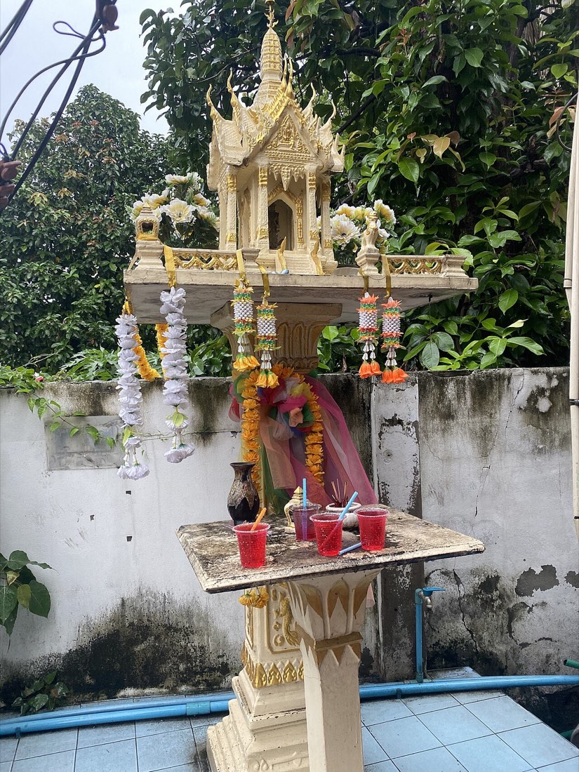 ศาลพระภูมิ มีน้ำแดงถวาย · a spirit house with red drinks set out for it