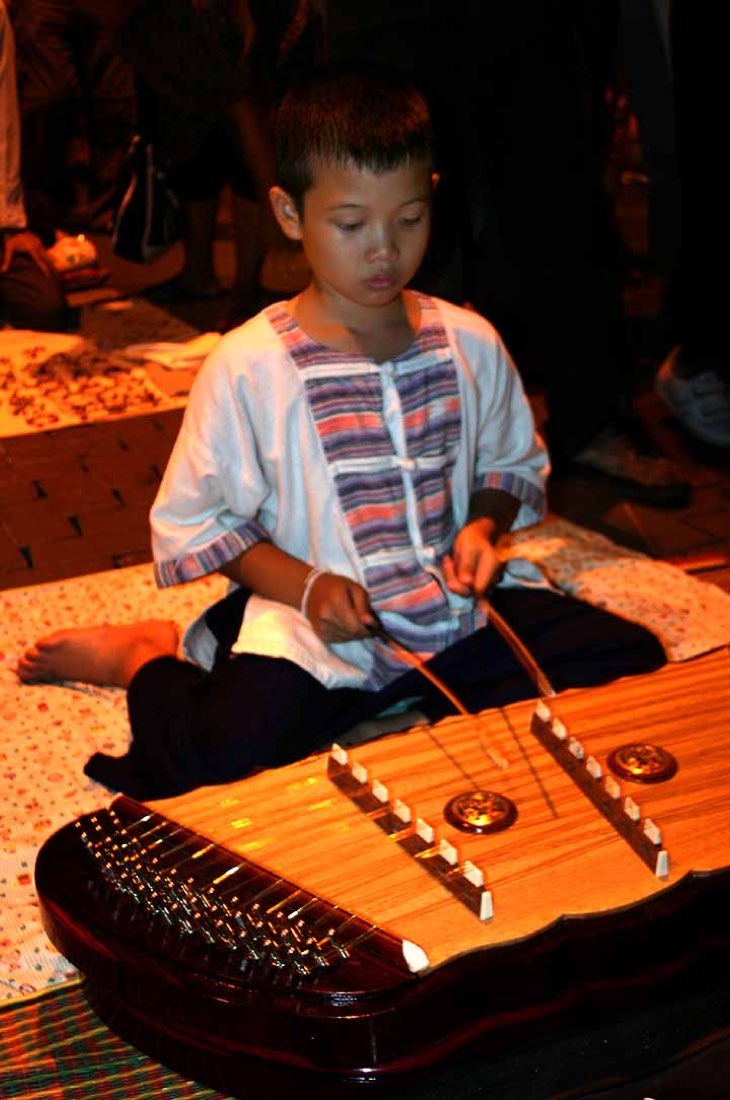 Sunday market, Chiangmai: A boy playing a khim , a traditional hammered dulcimer Thailand