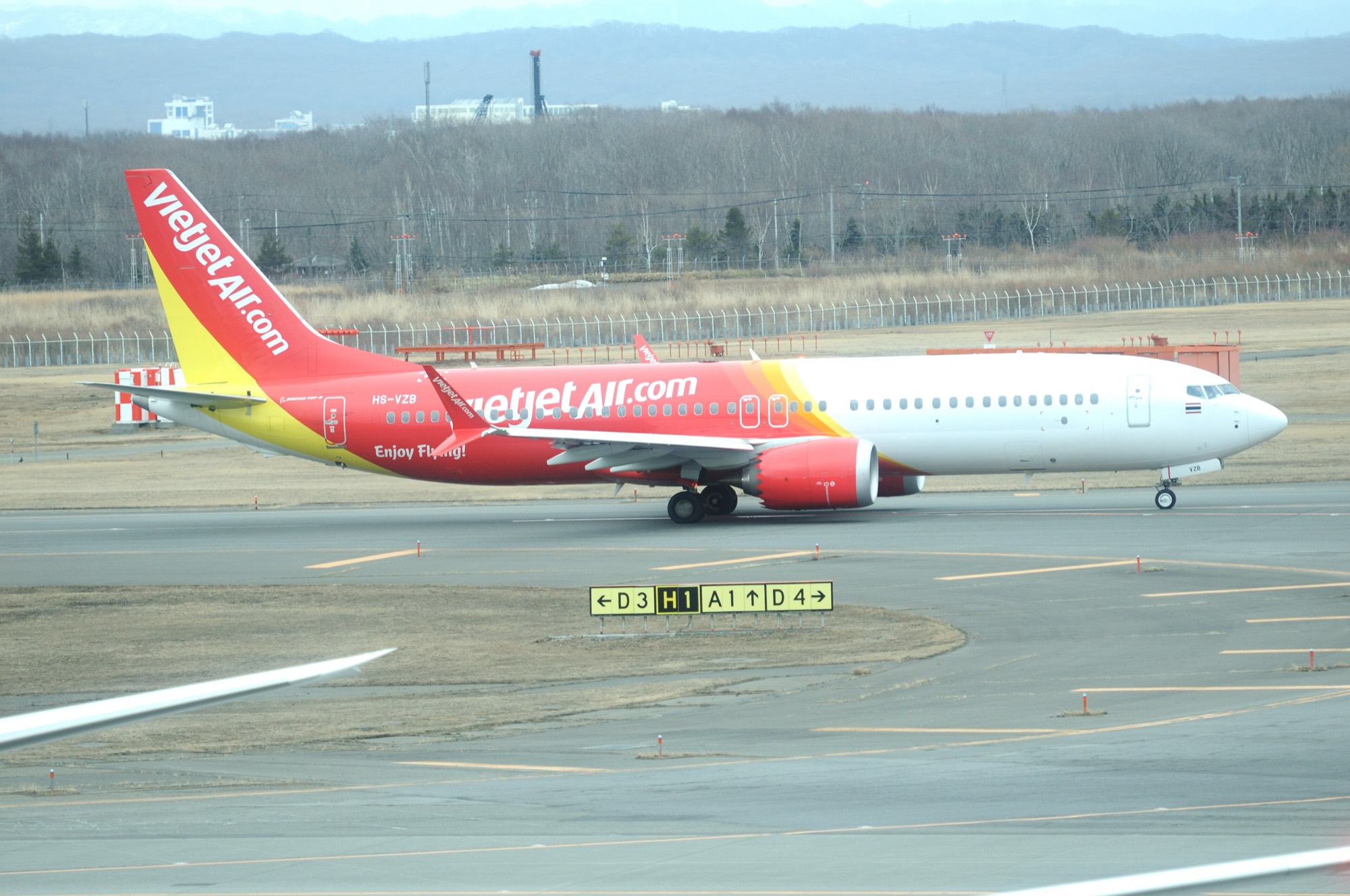 A red and white Thai Vietjet Boeing 737-8 MAX on a taxiway