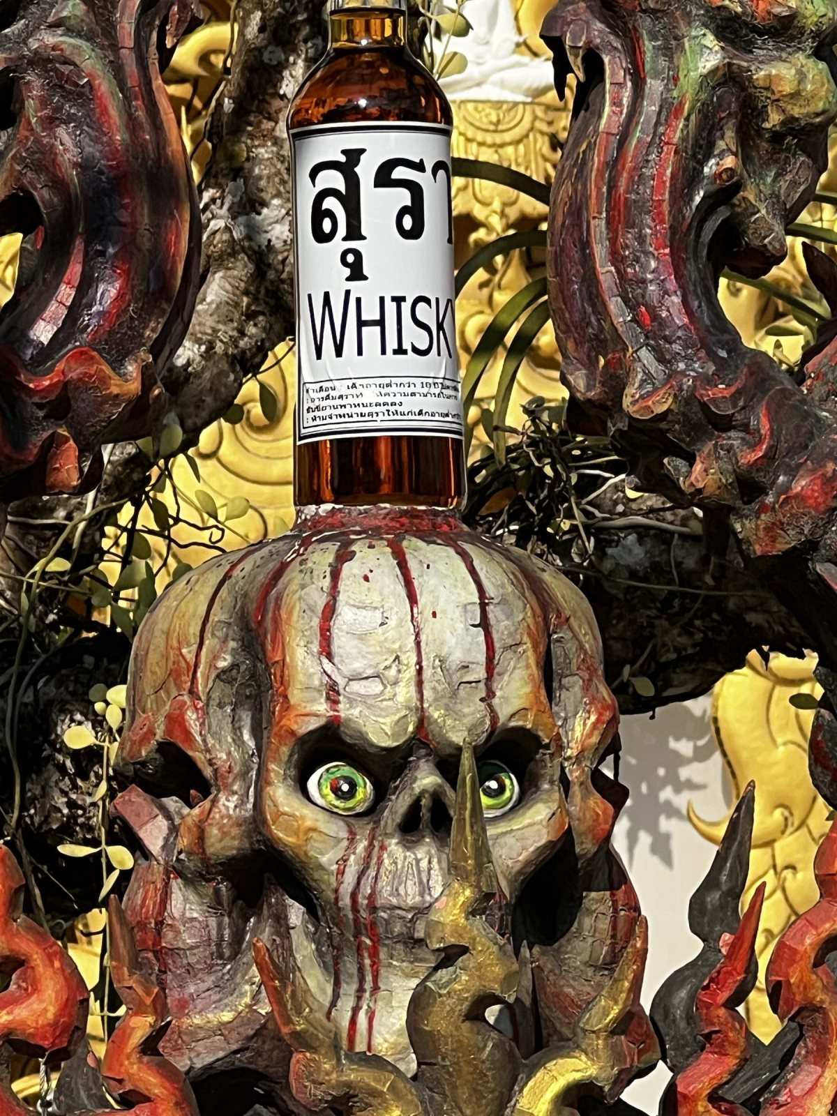 Wat Rong Khun: a skull with a whisky bottle.