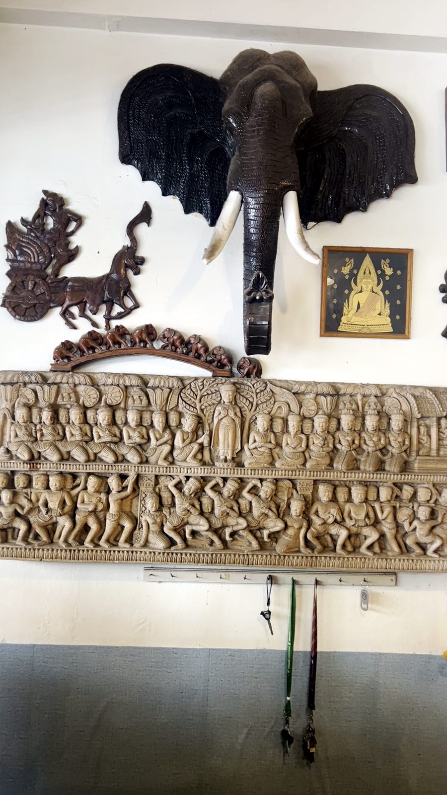 หัวช้าง เหนือแผงไม้แกะสลักเรื่องเล่า · an elephant head over the long carved story panel