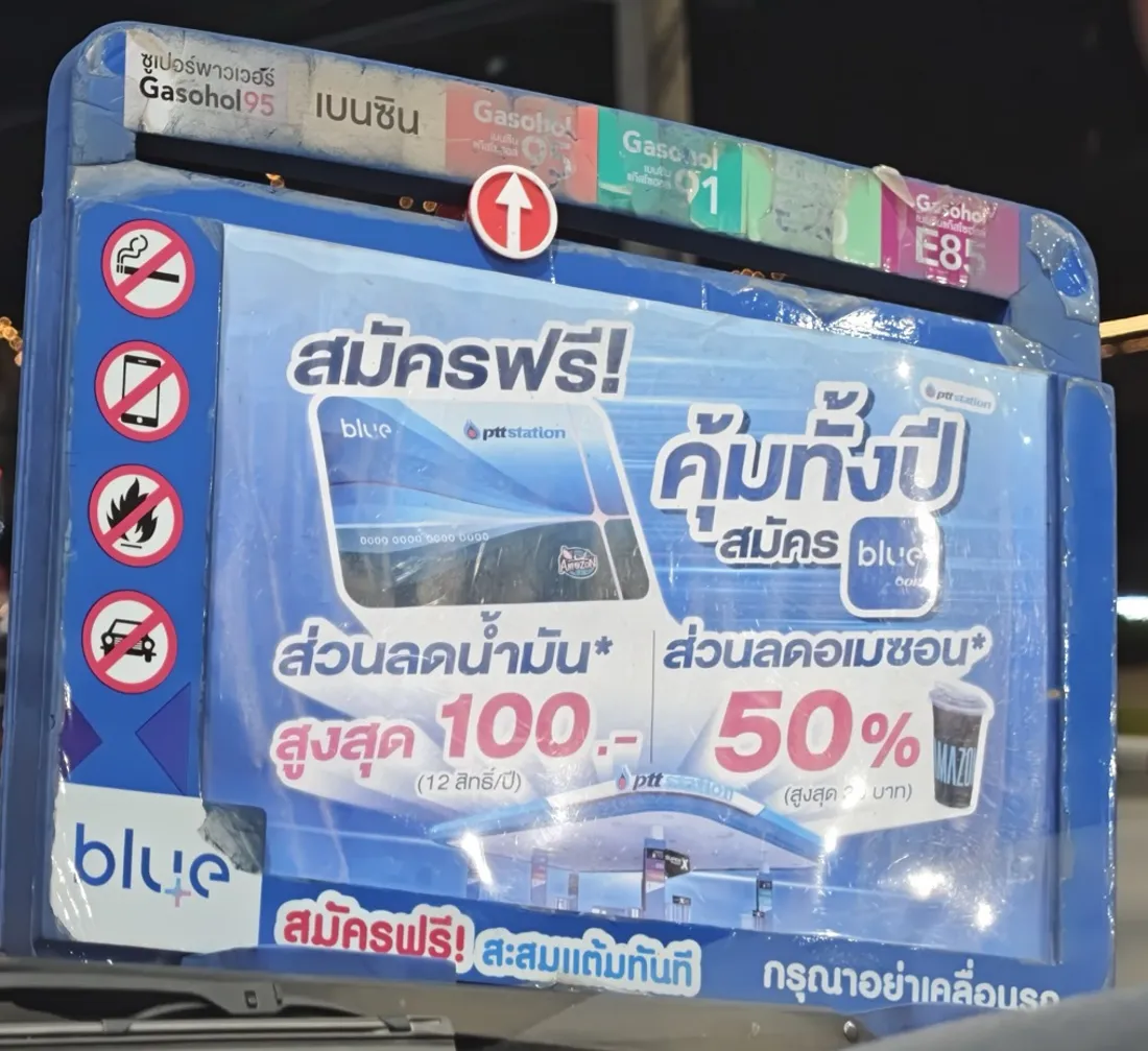 Blue magnetic sign on a car hood: six fuel labels along the top, a red arrow under Gasohol 95, four no-symbols down the left, an advertisement in the middle