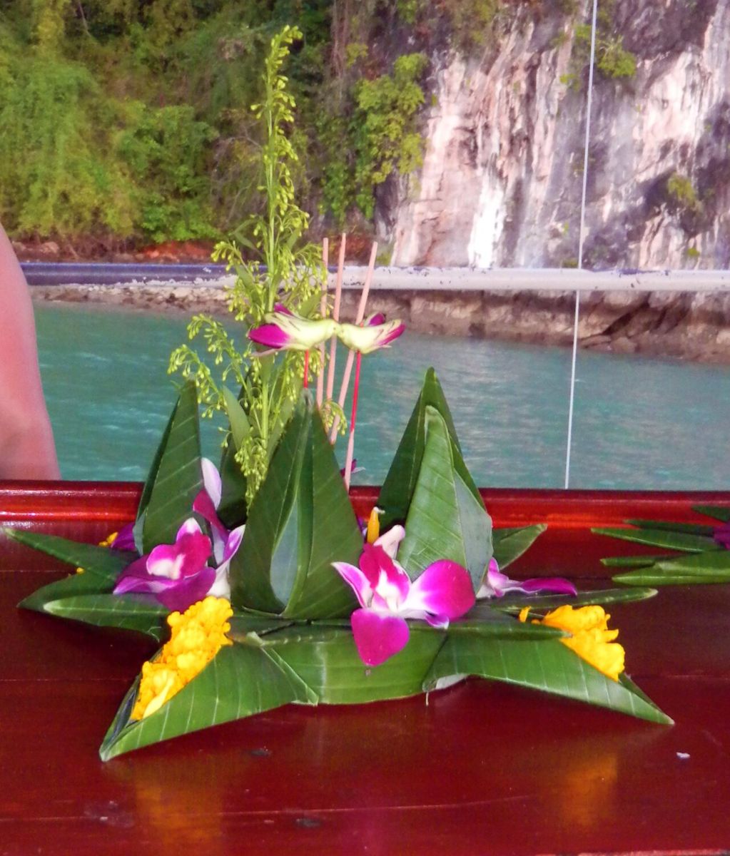 Folded leaf petals set in a star, with orchids, candle and incense.