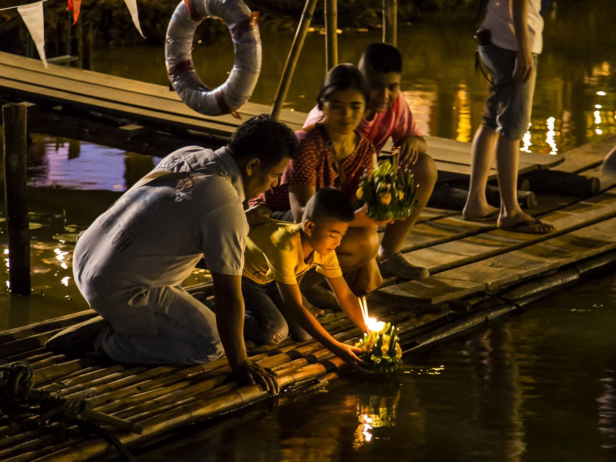 A family setting lit krathongs on the Ping from a bamboo raft, Chiang Mai, 2015.
