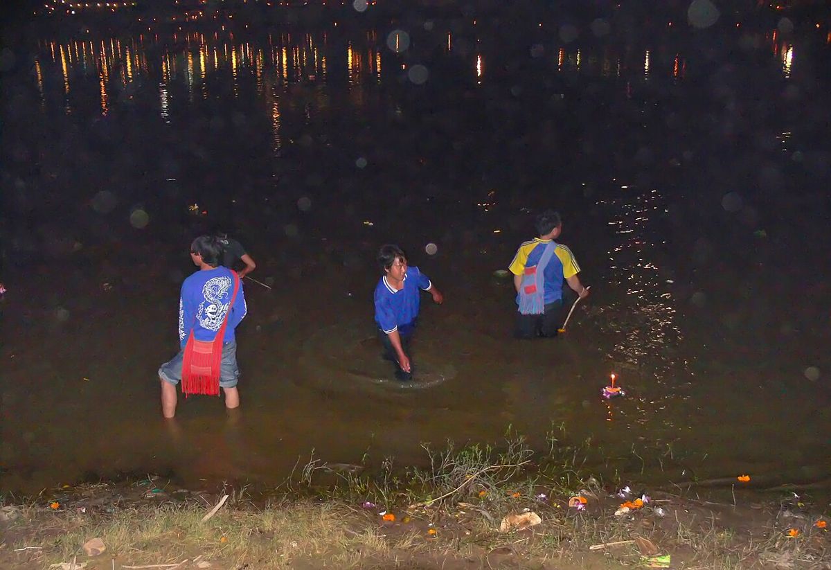 A few hundred metres downstream, people wade in to take the coins.
