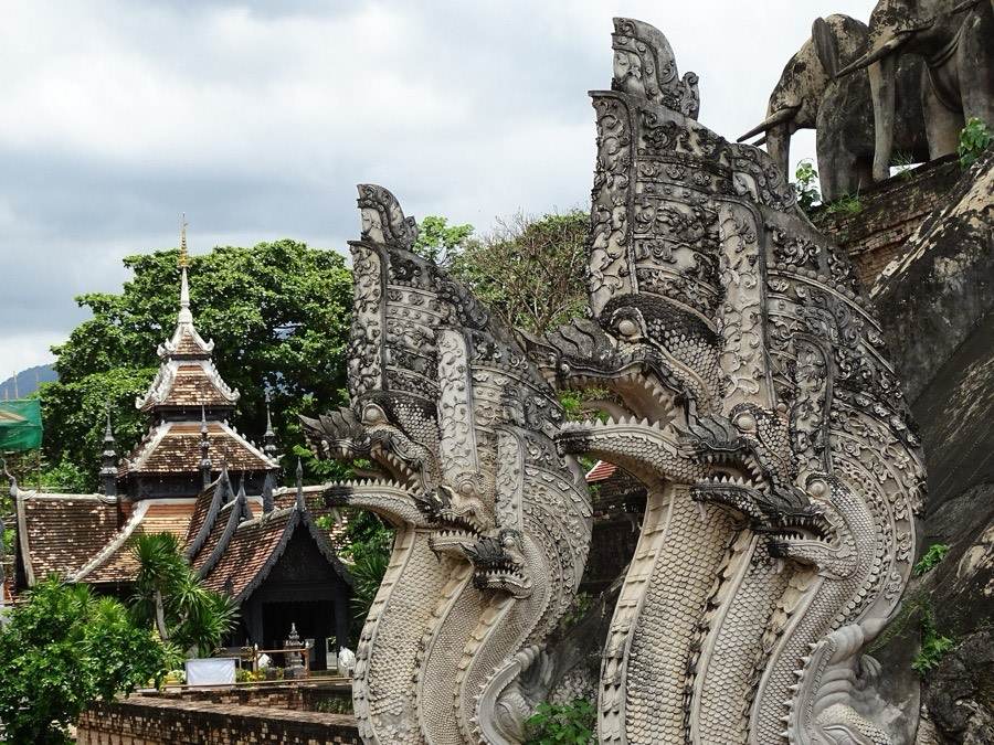 Stucco nagas rise beside the stair of the brick chedi.