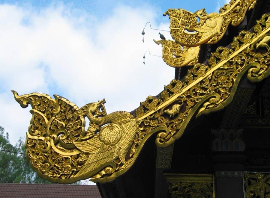 A gilded barge board curls into a naga tip at the gable.