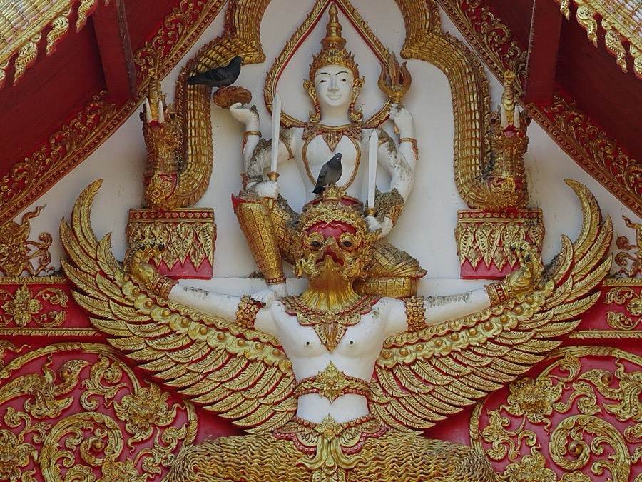 A deity rides a winged Garuda in the red-and-gold gable.