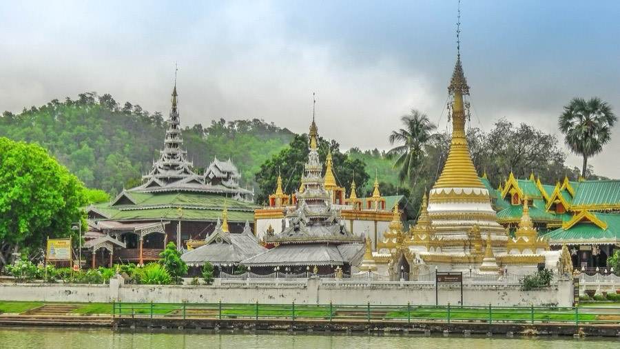 The Shan-style spires of two temples above a lake.