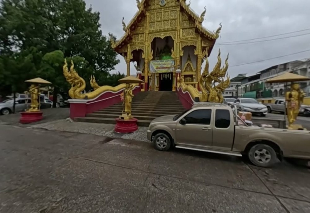 Golden ubosot front with naga stairs and golden standing figures under parasols