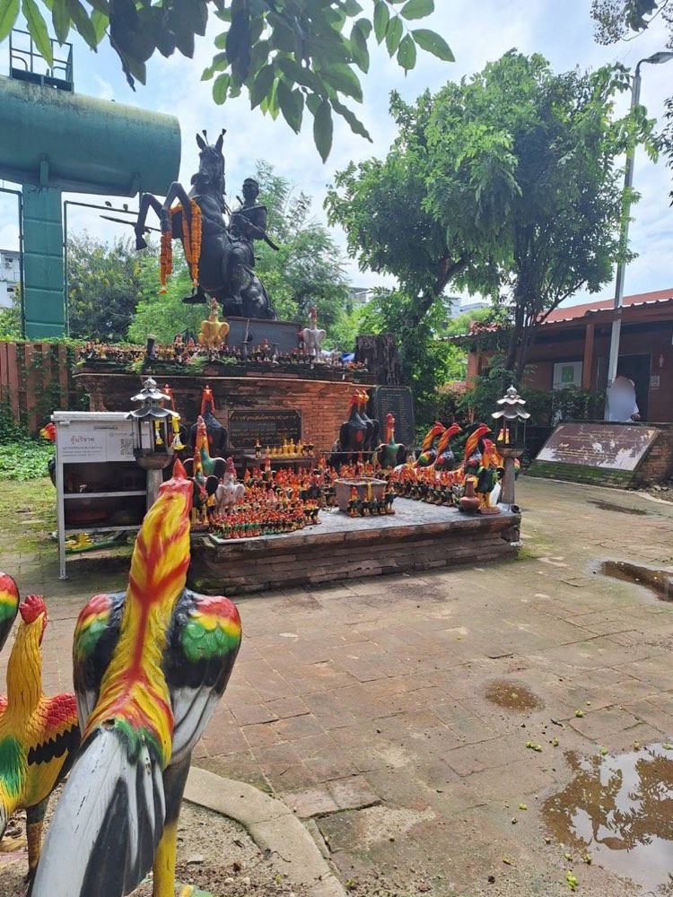 King Naresuan's shrine by Wat Lok Moli: the king on horseback over a brick base crowded with painted roosters