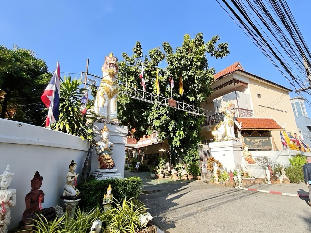 Wat Loi Khro's gate: white singha, guardian figures, flags, the lane in