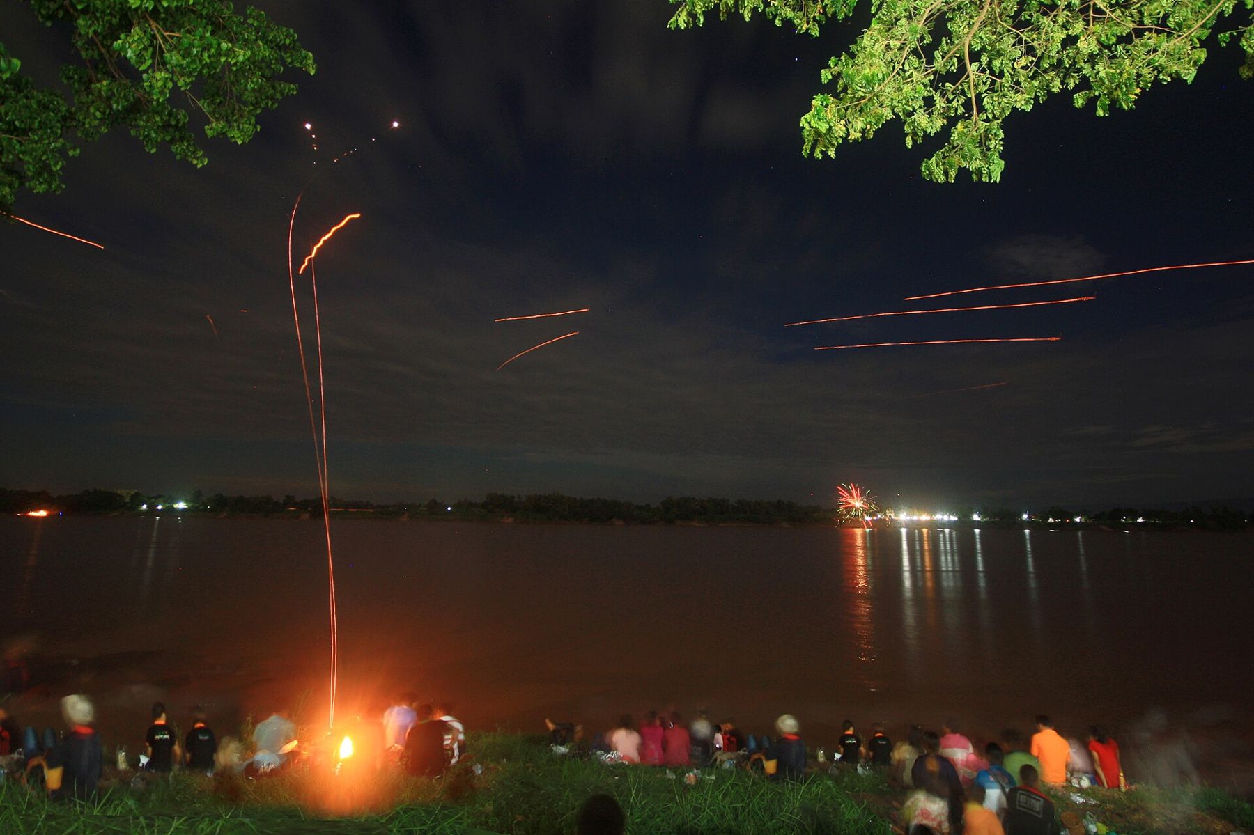A long exposure: a fireball's trail rising from the Mekong at Nong Khai, a crowd seated on the bank, 2013