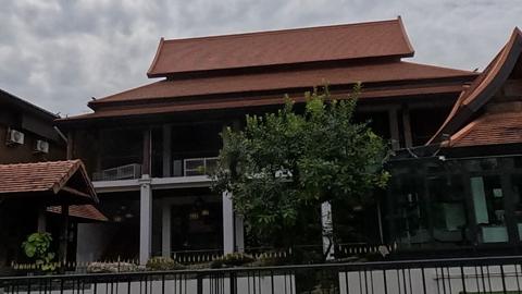 Lanna teak house behind an iron fence