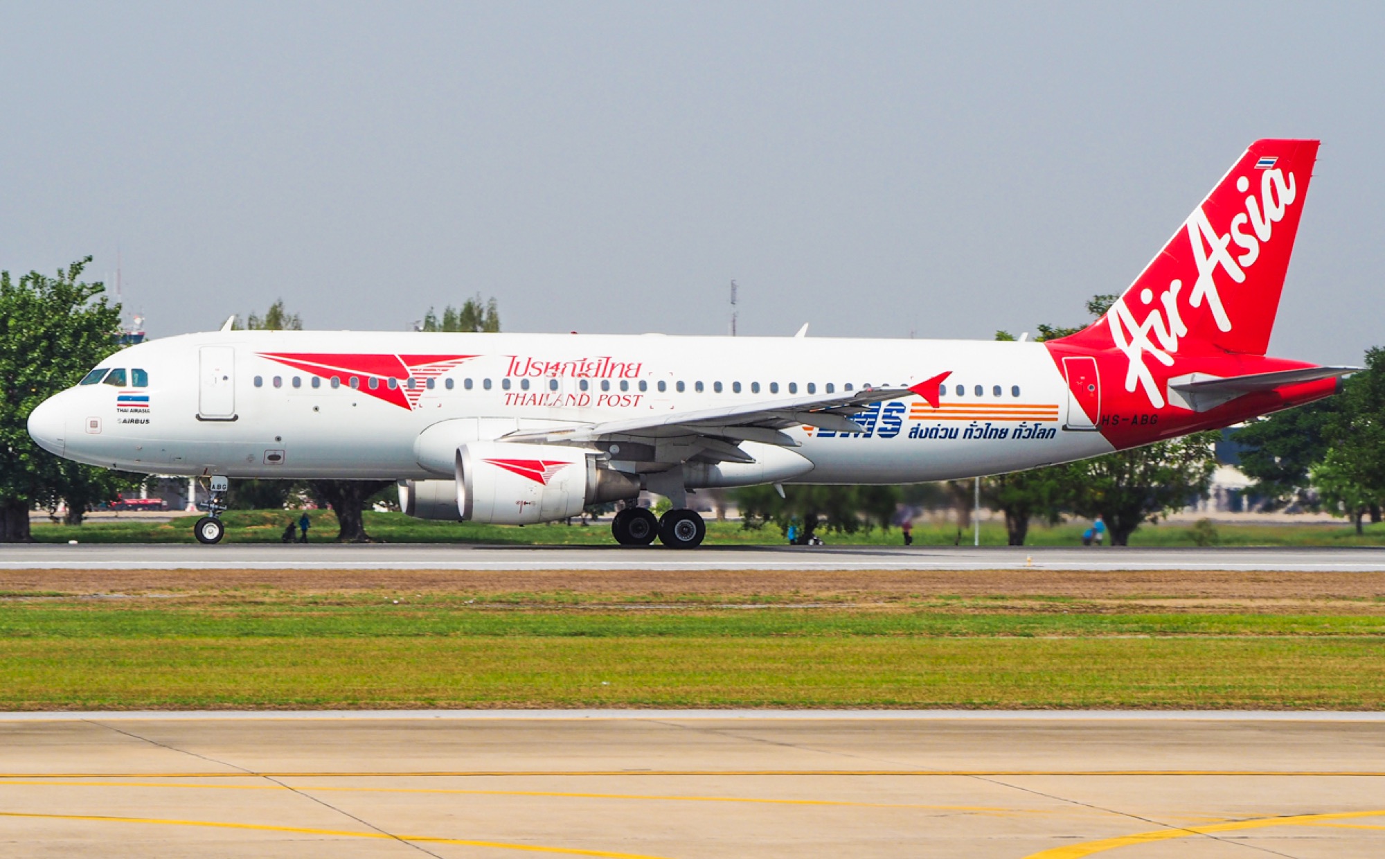An Airbus in white Thailand Post livery with a red AirAsia tail taking off from Don Mueang